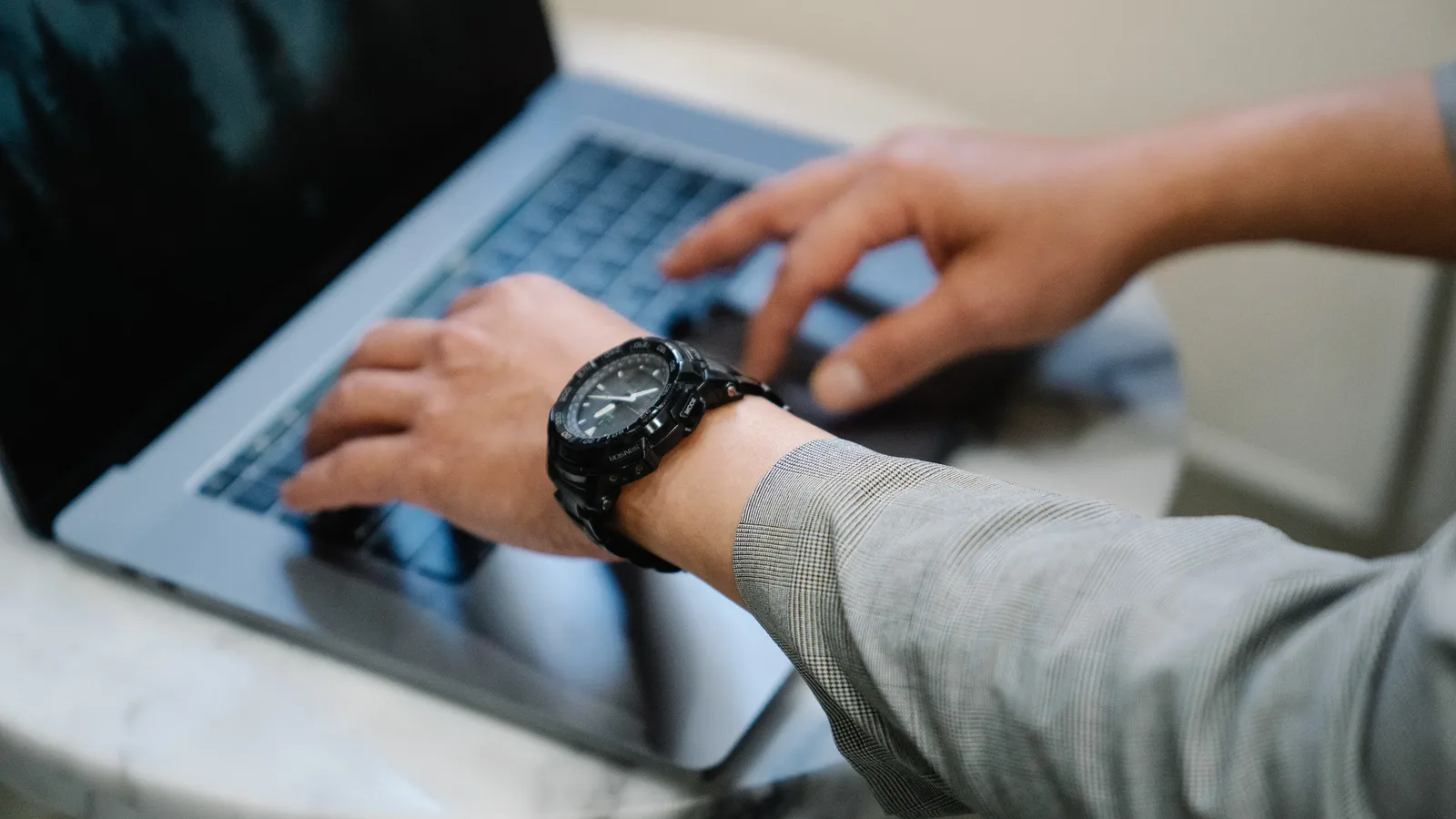 Hände tippen auf der Tastatur eines Laptops am Schreibtisch
