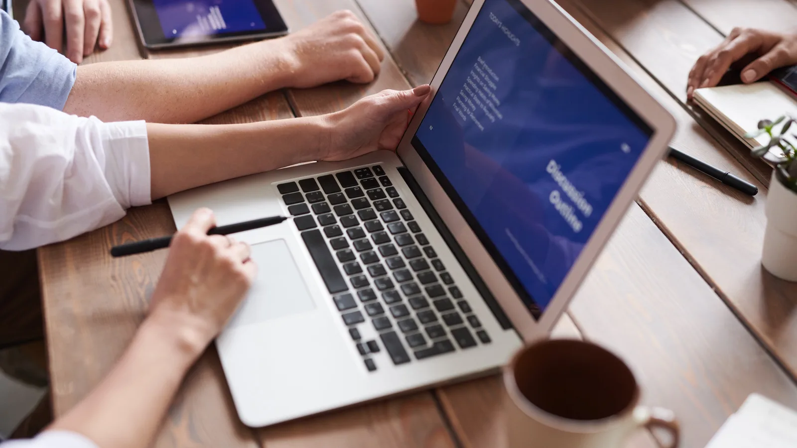 Zwei Menschen sitzen an einem Tisch vor einem aufgeklappten Laptop